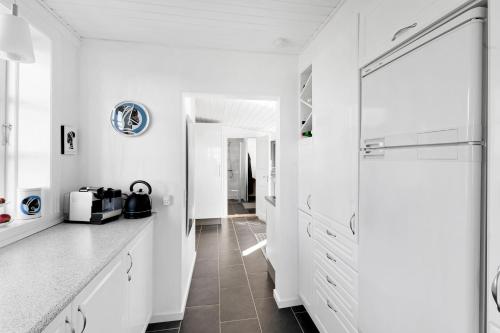 a white kitchen with white cabinets and a tile floor at Cottage With Breathtaking Sea And Cliff Views in Allinge