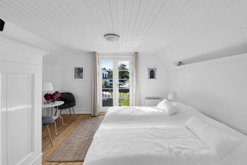 a white bedroom with a large bed and a table at Cottage With Breathtaking Sea And Cliff Views in Allinge