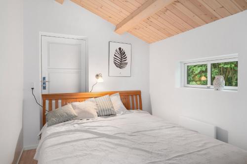 a white bedroom with a bed with a wooden headboard at Summer Cottage With Jacuzzi And Sauna in Fakse Ladeplads