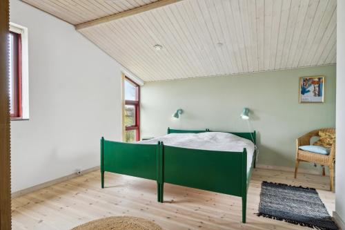 a bedroom with a green bed and a chair at Spacious Cottage Surrounded By Forest in Mesinge