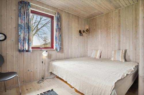 a bedroom with a bed in a wooden wall at Spacious Cottage Surrounded By Forest in Mesinge