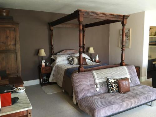 a bedroom with a canopy bed with a chair at The Clytha Arms in Abergavenny