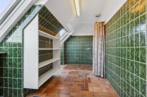a bathroom with green tiled walls and a window at House For 40 People Near Thy in Gettrup