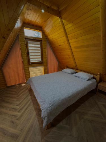 a bedroom with a bed in a wooden cabin at Vlasic Odmor - Villa Krajina IV & jacuzzi in Vlasic