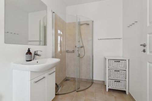 a white bathroom with a sink and a shower at Holiday Apartment For 4 With Shared Pool in Åkirkeby