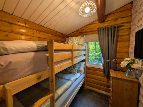 two bunk beds in a log cabin with a window at Cabin Aelwyd Snowdonia in Trawsfynydd