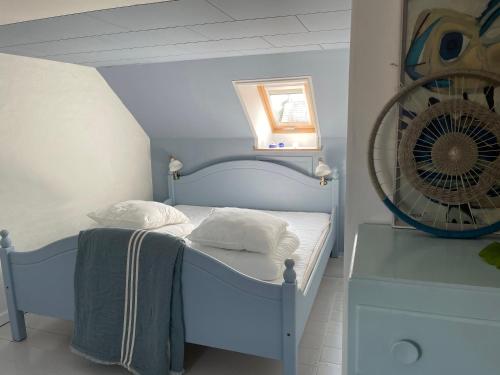a small bedroom with a blue bed and a fan at Tordenskjoldet in Marstal