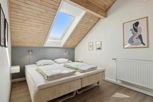 a bedroom with a large bed with a skylight at Summer House On Beautiful Rømø in Sønderby