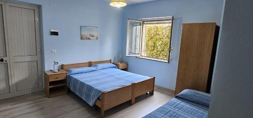 a blue bedroom with a bed and a window at Residenza Laura Casa Vacanze Capo Vaticano in Capo Vaticano