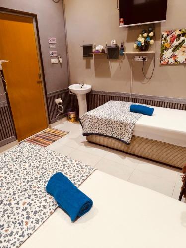 a room with two beds and a sink and a bathroom at Desa Besut Inn in Kampung Kuala Besut