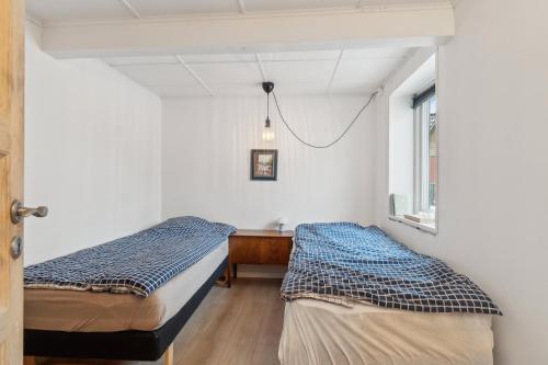 two beds in a room with a desk and a window at Cosy House Near Forest in Rønne