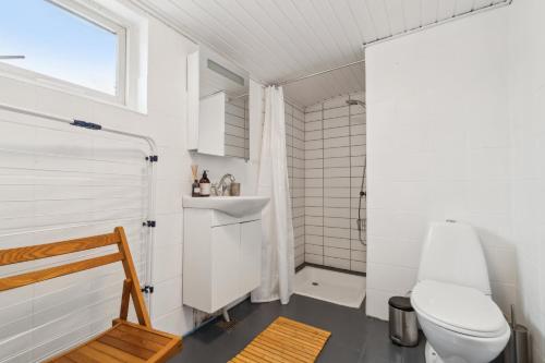 a white bathroom with a toilet and a sink at Cosy House Near Forest in Rønne