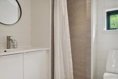 a bathroom with a white shower curtain and a mirror at Scenic Summer House In Asserbo in Frederiksværk