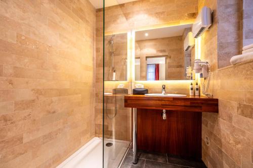 a bathroom with a sink and a shower at Hôtel Amphithéâtre in Arles
