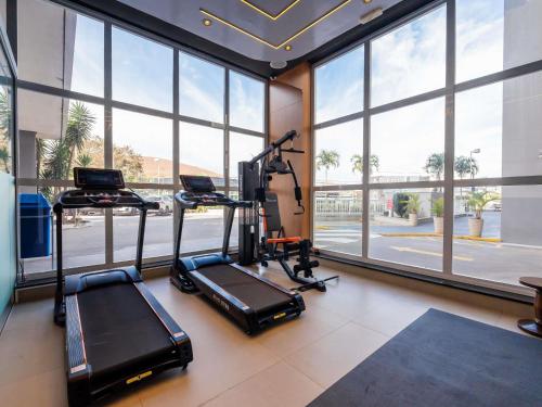 a gym with treadmills and ellipticals in a room with windows at Ibis Guaratingueta Aparecida - Circuito da Fé in Guaratinguetá