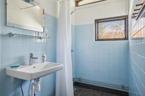 a blue tiled bathroom with a sink and a window at Cozy Cottage Near Bjerge Strand in Store Fuglede