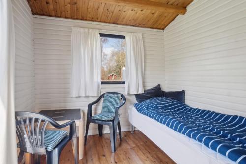 a bedroom with a bed and two chairs and a window at Cozy Cottage Near Bjerge Strand in Store Fuglede