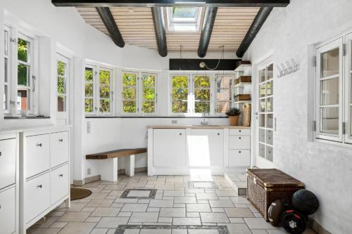 a kitchen with white cabinets and a table and windows at Togetherness Coziness Magical Great Belt View in Tranekær