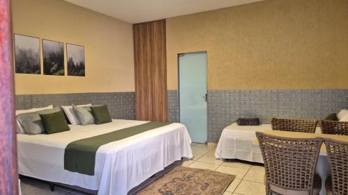 a hotel room with two beds and two chairs at Suítes privativas, camas confortáveis, piscina, churrasqueira e playground, Roupa de Cama e tolha de banho. in Rubinéia
