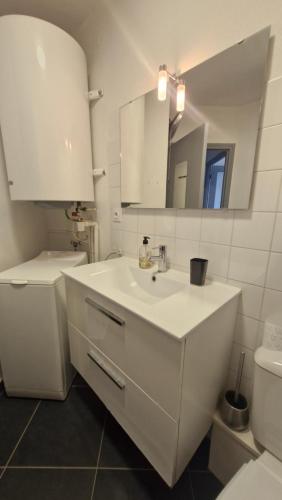 a white bathroom with a sink and a mirror at Grand T3 face au port avec sa terrasse , parking privatif in Saint-Cyprien-Plage