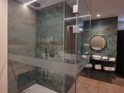 a bathroom with a glass shower with a sink at Motel Unique Private Suites in Leça da Palmeira