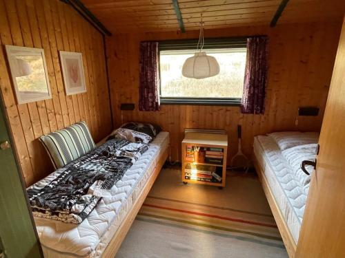 a room with two beds in a cabin with a window at 70S Charm Just 300 M From The Beach in Blokhus