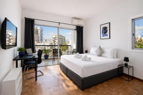 a bedroom with a bed and a desk and a balcony at Urban Condo Promitheos in Nicosia