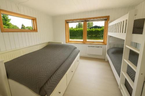 a bedroom with two bunk beds and two windows at The Pearl In Marielyst in Bøtø By