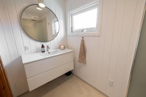 a white bathroom with a sink and a mirror at The Pearl In Marielyst in Bøtø By