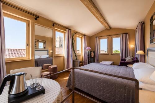 a bedroom with a bed and a table and chairs at Hôtel Amphithéâtre in Arles