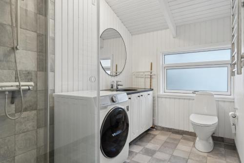 a bathroom with a washing machine and a toilet at Cozy Holiday Home On Orø in Orø