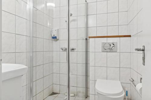 a white bathroom with a shower and a toilet at Pension Koch Apartment 6 in Gudhjem