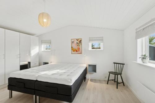 a white bedroom with a large bed and a chair at Quiet Holiday Home With Annex And Great Outdoor in Bogø By