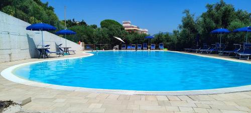 a large swimming pool with blue chairs and umbrellas at Villaggio Club Tortorella in Marina di Casalvelino