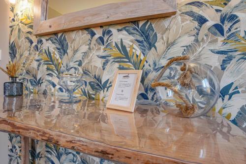 a counter with a glass bowl on a wall with tropical wallpaper at Les halles du temps in Bar-sur-Seine