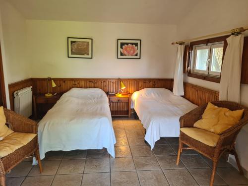 a bedroom with two beds and chairs and a window at El Valle in Piedralaves