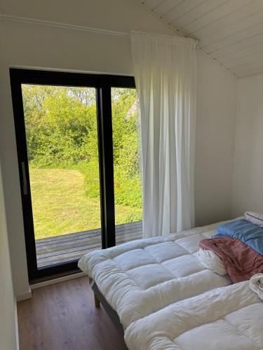 a bedroom with two beds and a large window at Stylish Cottage Near Beach Cliffs Harbour in Havnelev