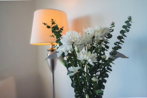 a vase filled with white flowers next to a lamp at Delta Boutique Loft, en el centro de Salta, para 3 by BEDBOOK in Salta