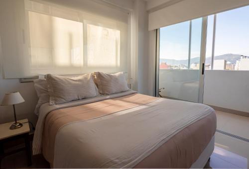 a bedroom with a large bed with a large window at Delta Boutique Loft, en el centro de Salta, para 3 by BEDBOOK in Salta