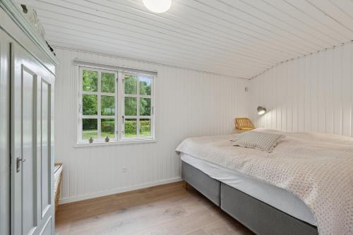 a white bedroom with a bed and a window at Renovated Classic Cottage Close To Beach in Roslev