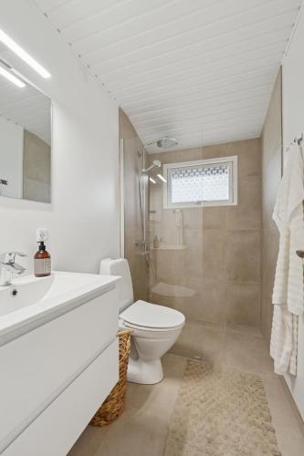 a white bathroom with a toilet and a sink at Renovated Classic Cottage Close To Beach in Roslev