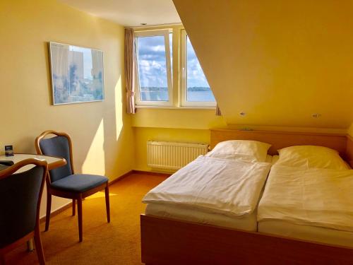 a bedroom with a bed and a chair and a window at Hotel Kieler Förde & Free Parking in Kiel