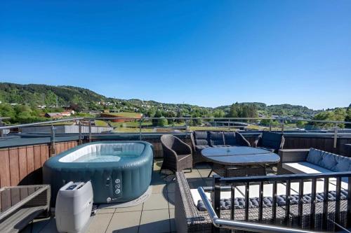 a balcony with a hot tub and tables and chairs at Penthouse with Rooftop Terrace & Balcony in Bergen