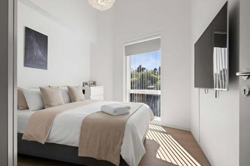 a white bedroom with a large bed and a window at Penthouse with Rooftop Terrace & Balcony in Bergen