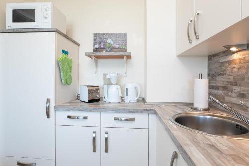 a kitchen with white cabinets and a sink at Strandhotel Dahme TraumMeerBlick in Dahme