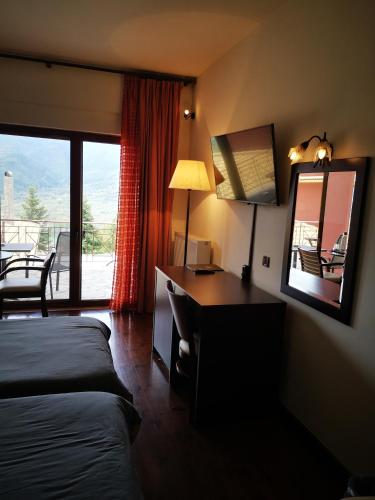a bedroom with a desk and a bed and a mirror at Olvios Hotel in Goura