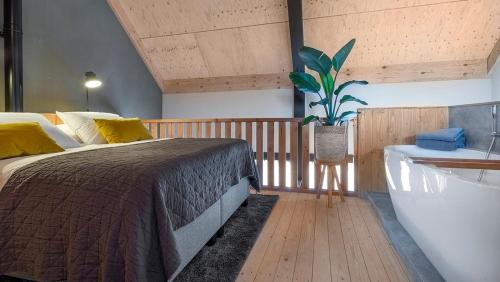 a bedroom with a bed and a tub and a plant at Lennepserf - De Hoeven in Veessen