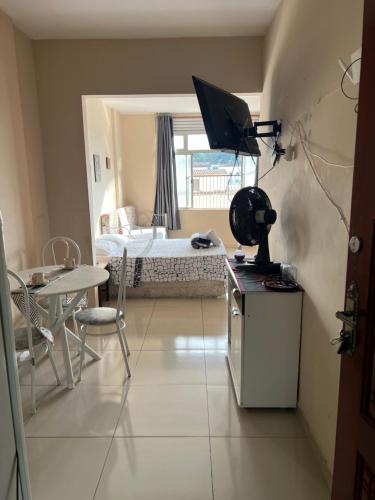 a small room with a bed and a table with a television at Suítes São Lourenço in São Lourenço