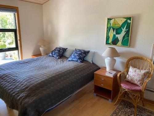 a bedroom with a bed and a chair and a window at Veddinge Odsherreddenmark - House With Seaview in Asnæs
