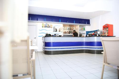 a bar in a restaurant with a man standing at the counter at Hotel Meli in Castelsardo
